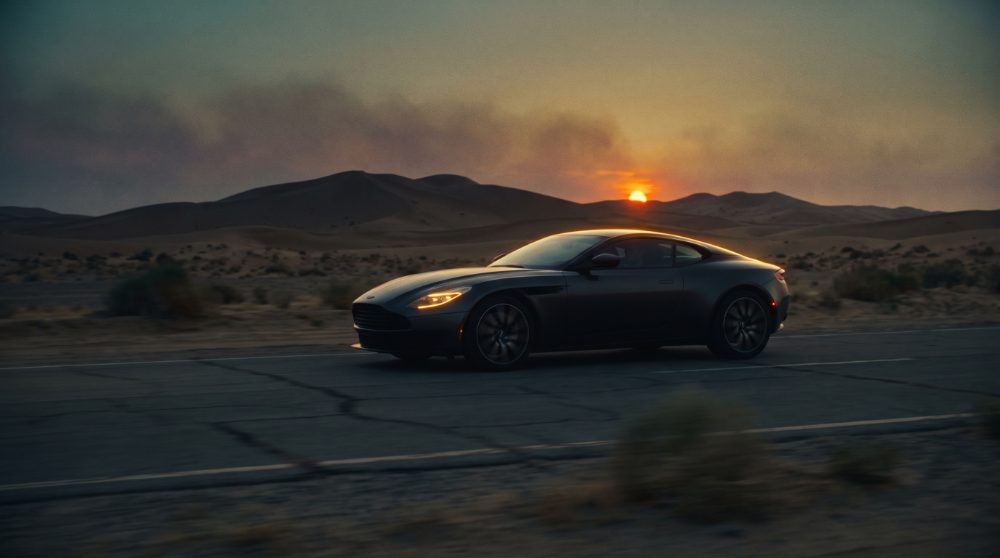 Automotive film still — coupé on a desert road at sunset