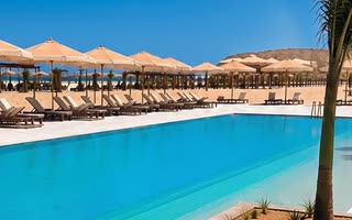 A resort pool with parasols under a clear sky